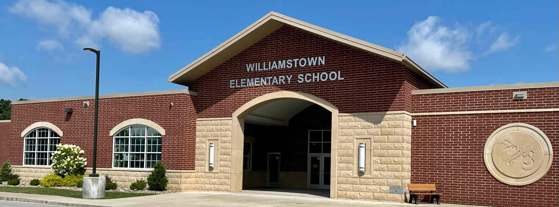 outside view of williamstown elementary school building with parking lot in front and a blue sky with limited clouds