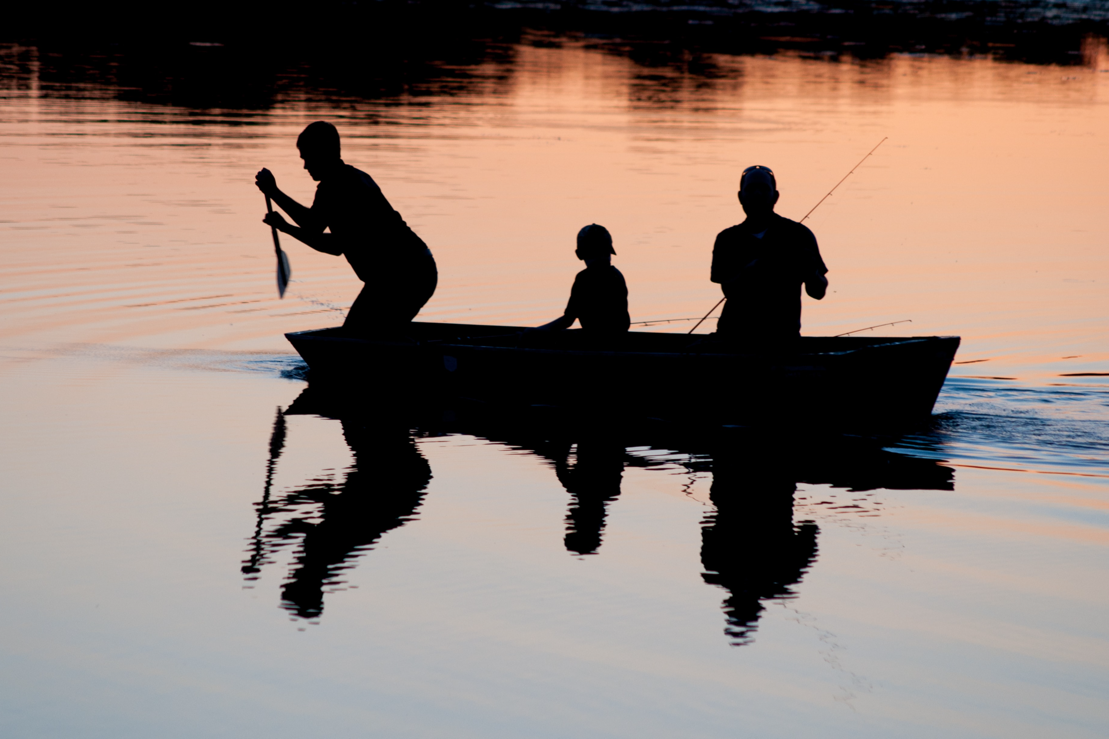family fishing on lake at sunset