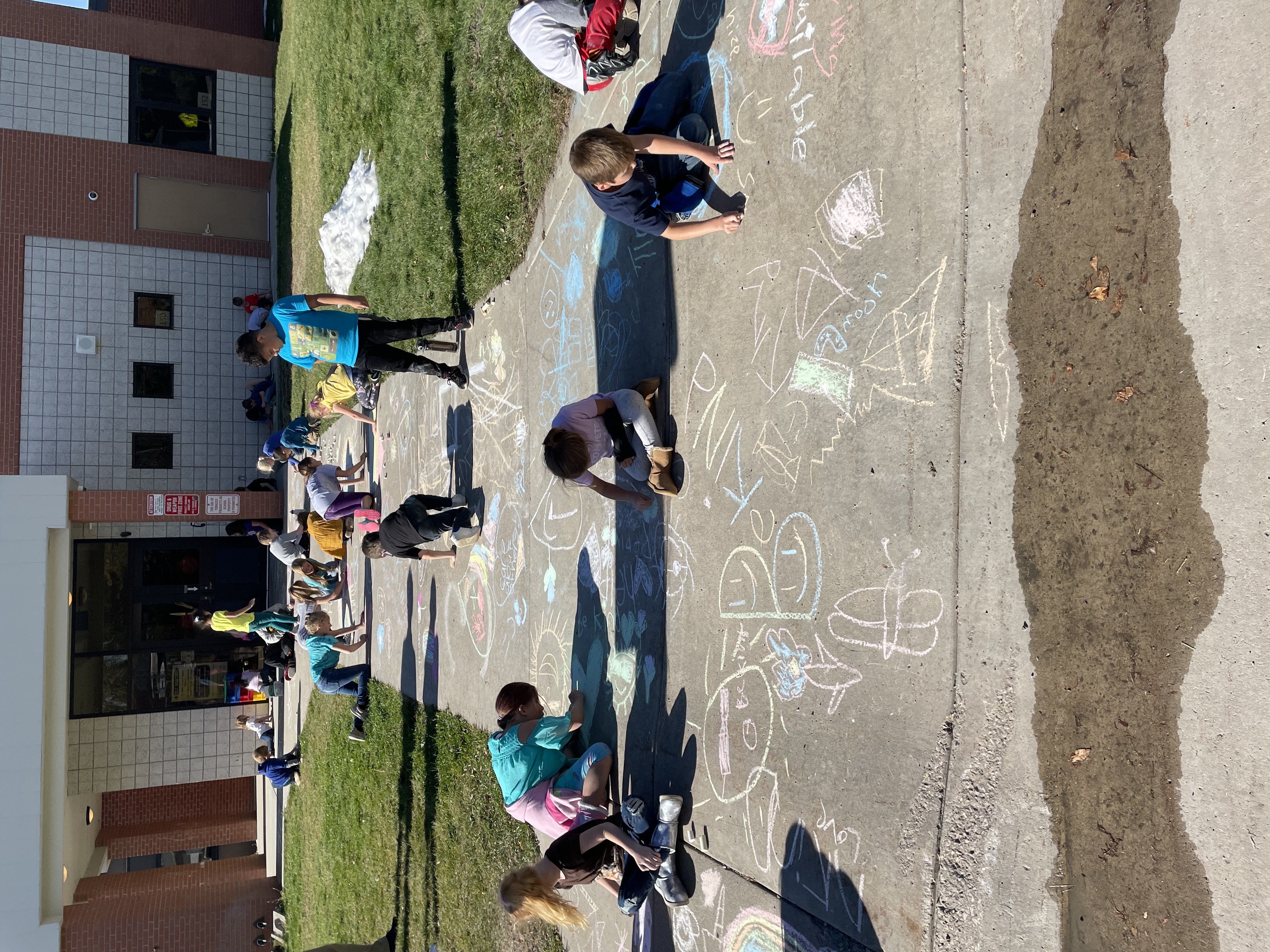 1st and 3rd Graders chalk the sidewalks encouraging unity