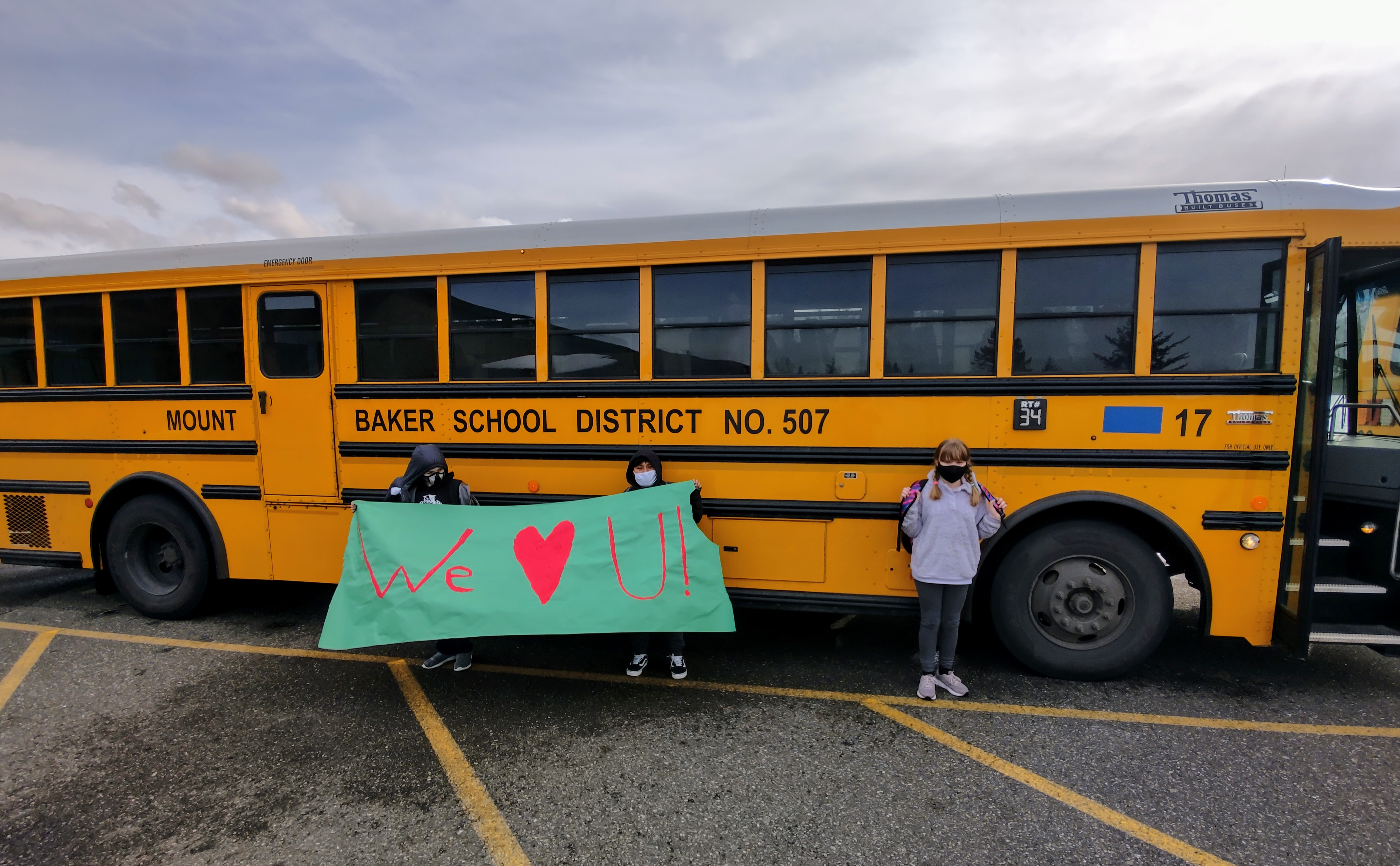 Students Holding Banner that reads, "We Love You," Red Heart on Banner, School Bus