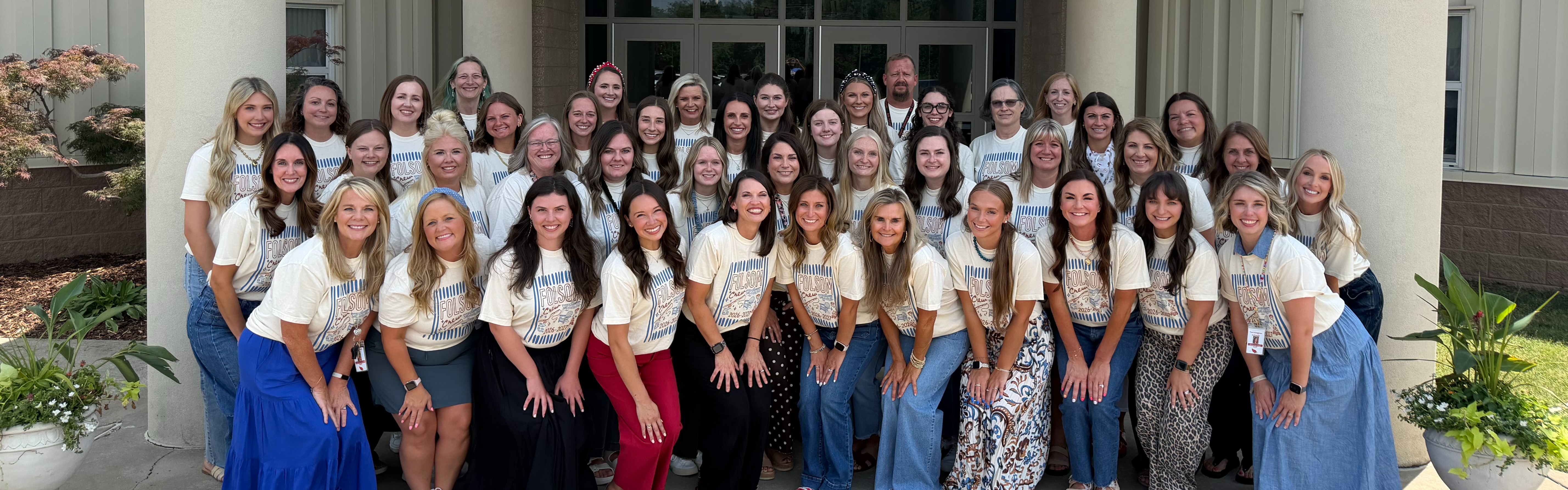 A group of women in white shirts pose for a photo in front of a building.