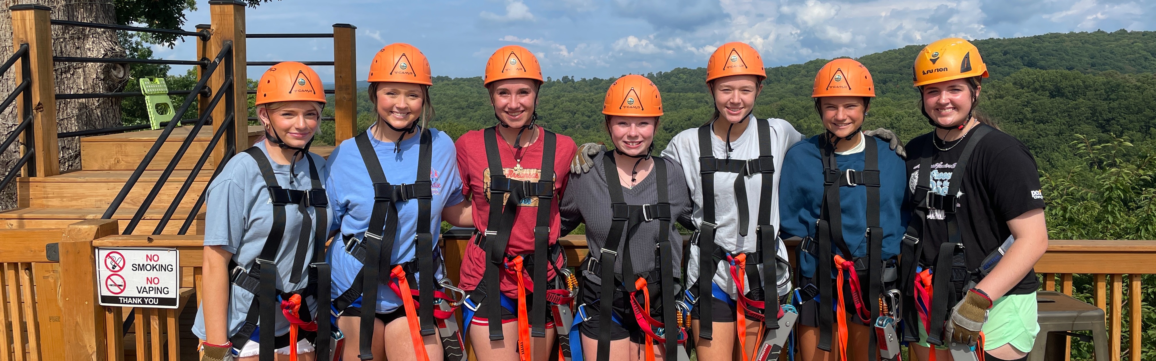 students posing in a line at a zip line