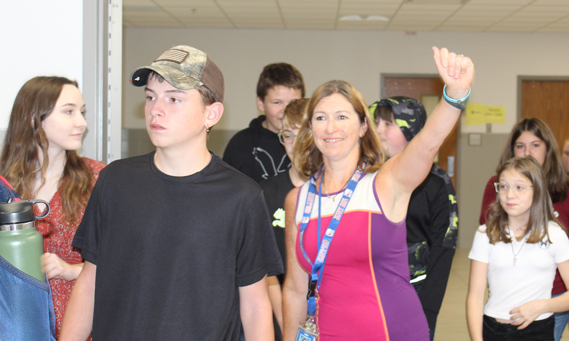 students and teacher in hallway, teacher waving