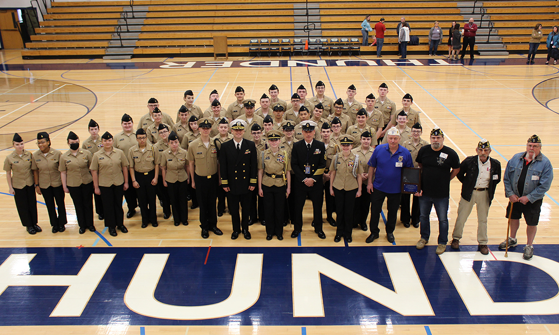 large group of cadets, officers, veterans standing on gym floor