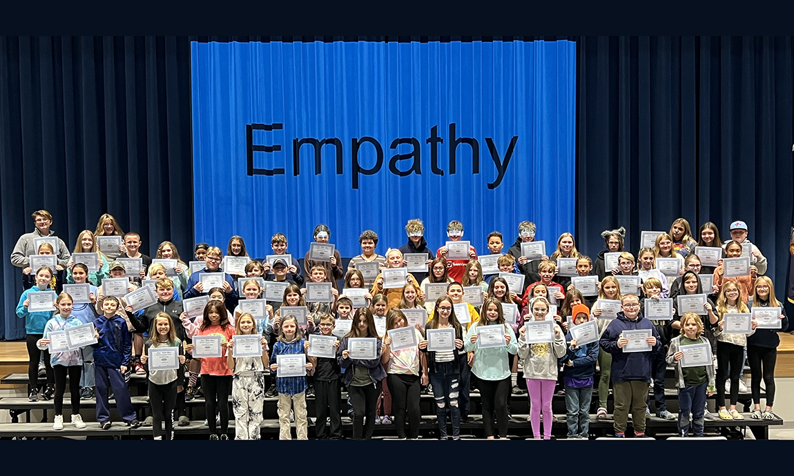 large group of students on risers with giant empathy sign