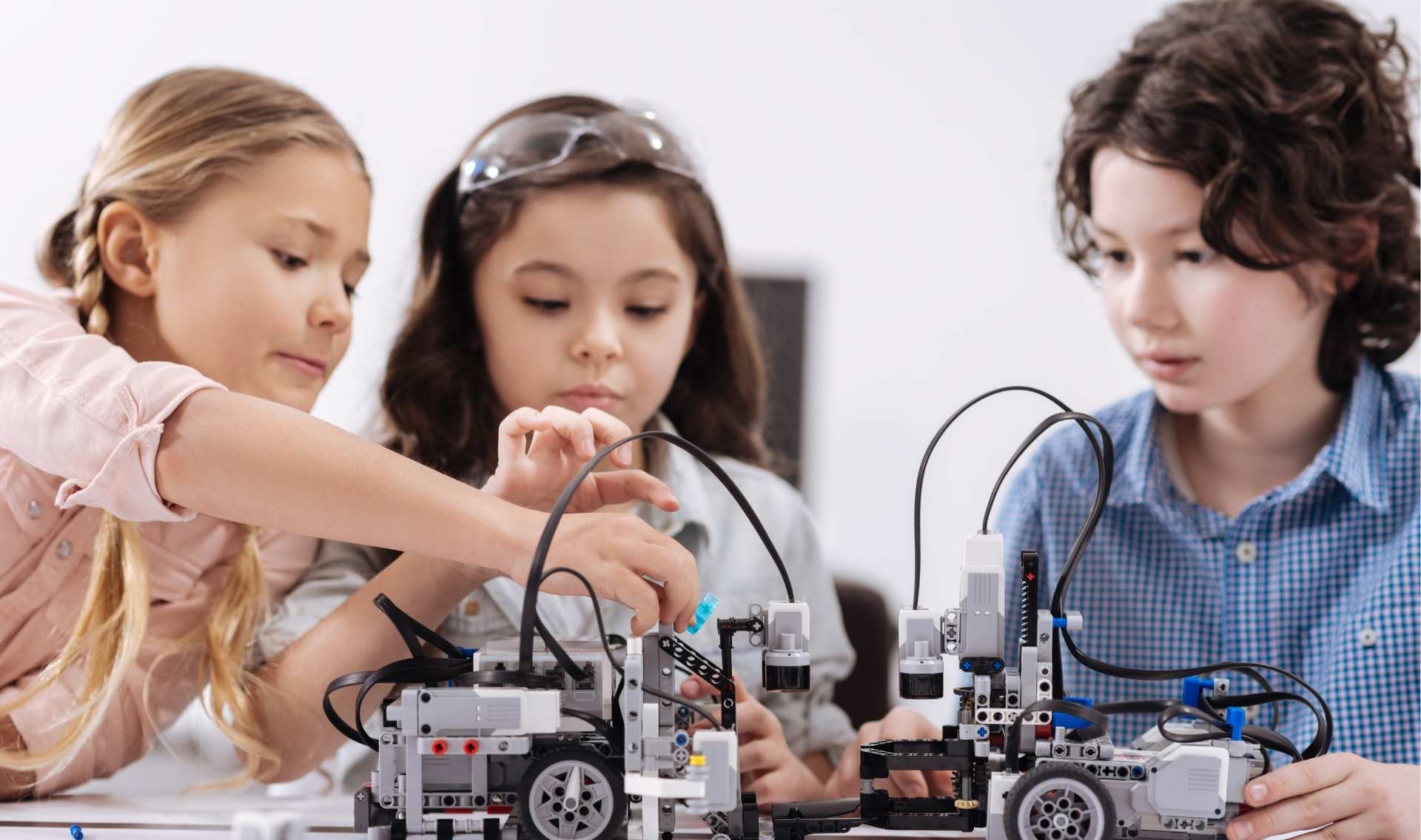 three younger students working with robotic STEAM tools