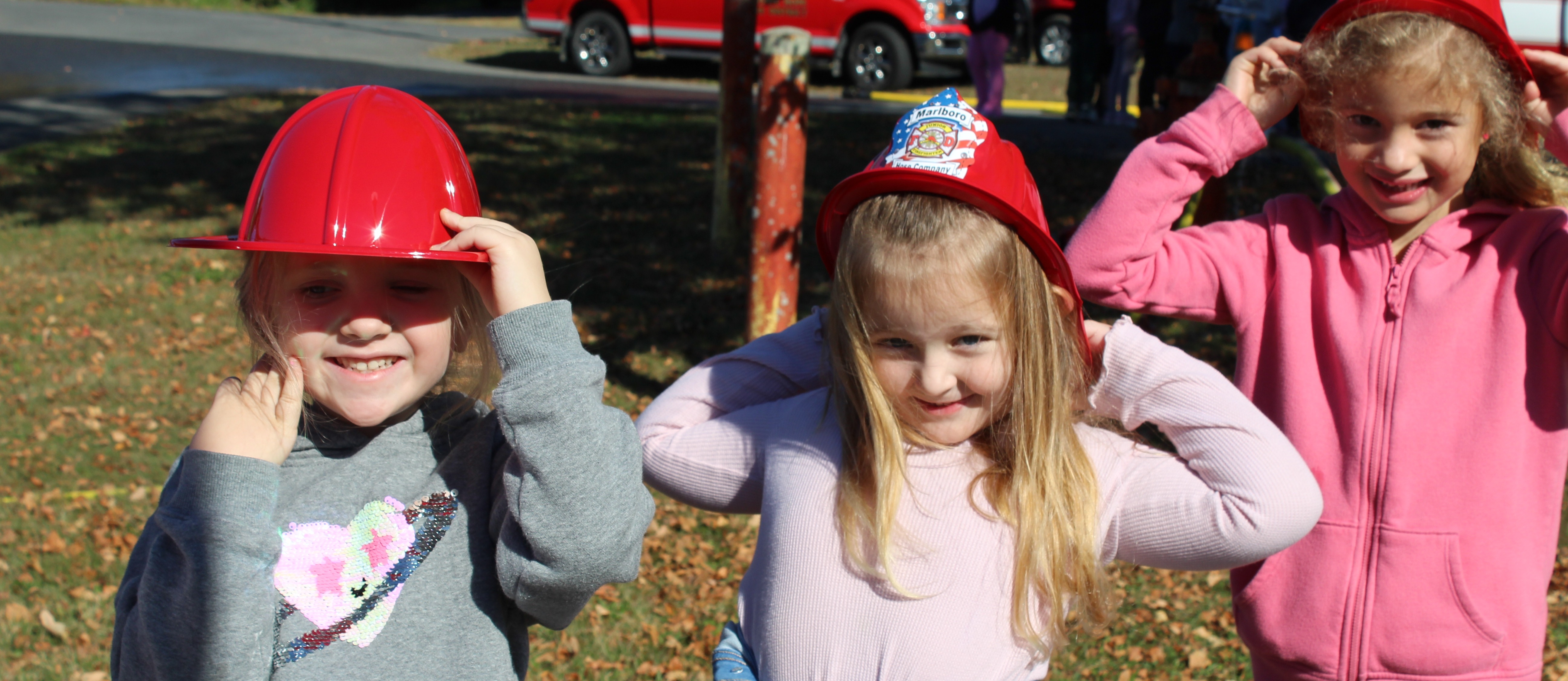 Three young students wearing fire hats