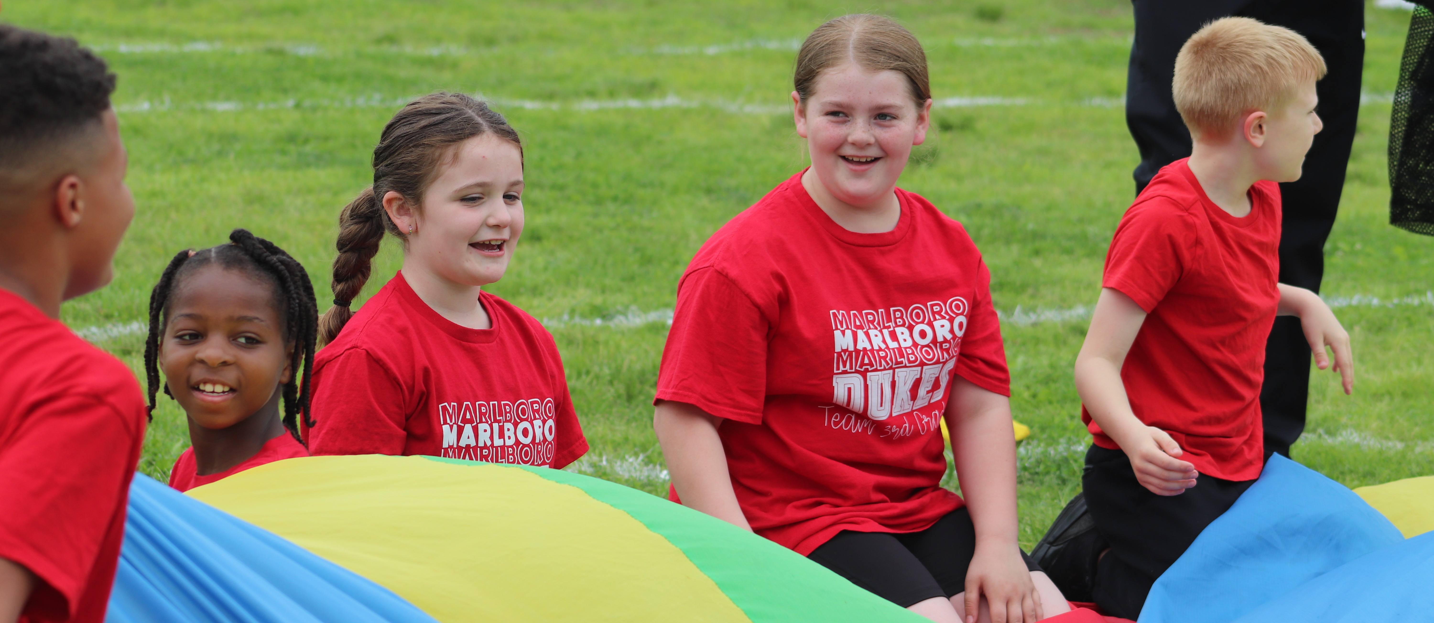 Students smiling while holding a parachute