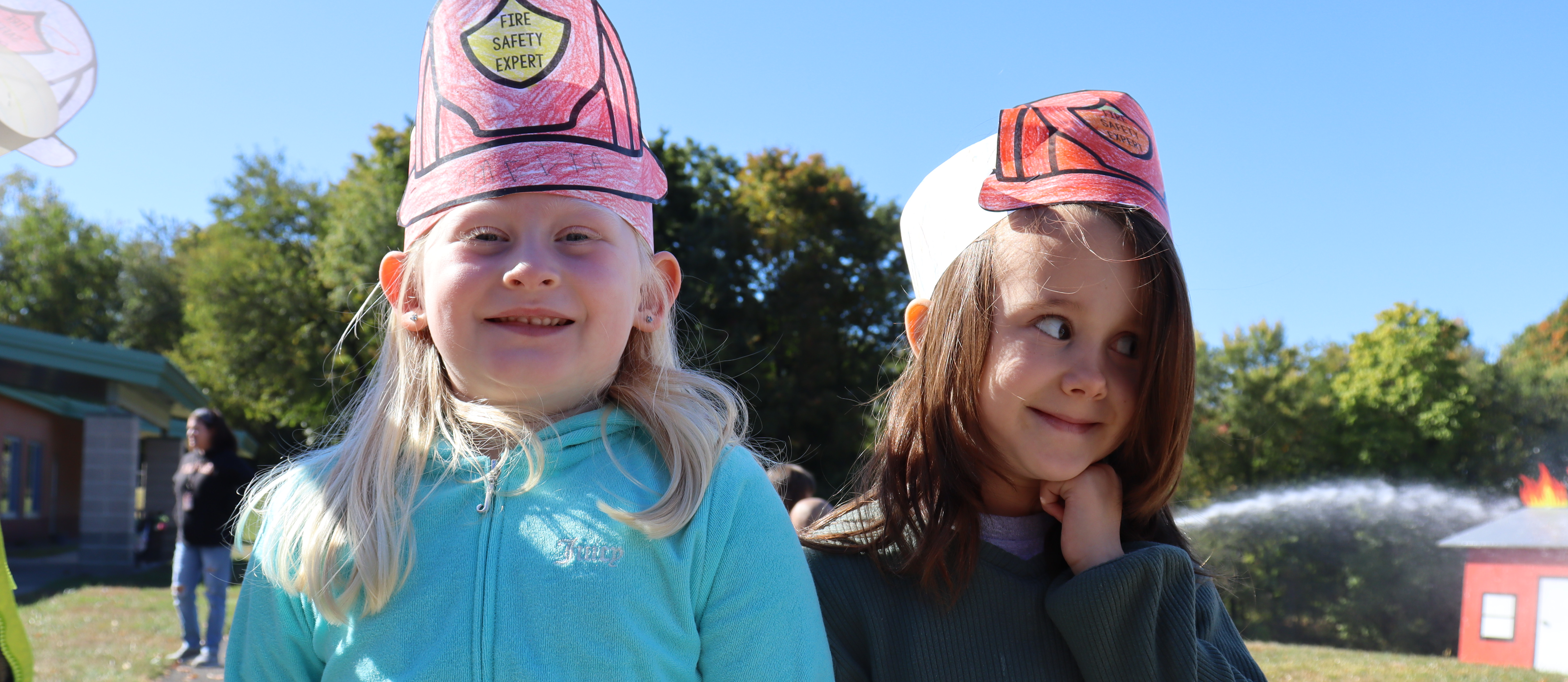 Two students wearing fire safety paper crowns outside