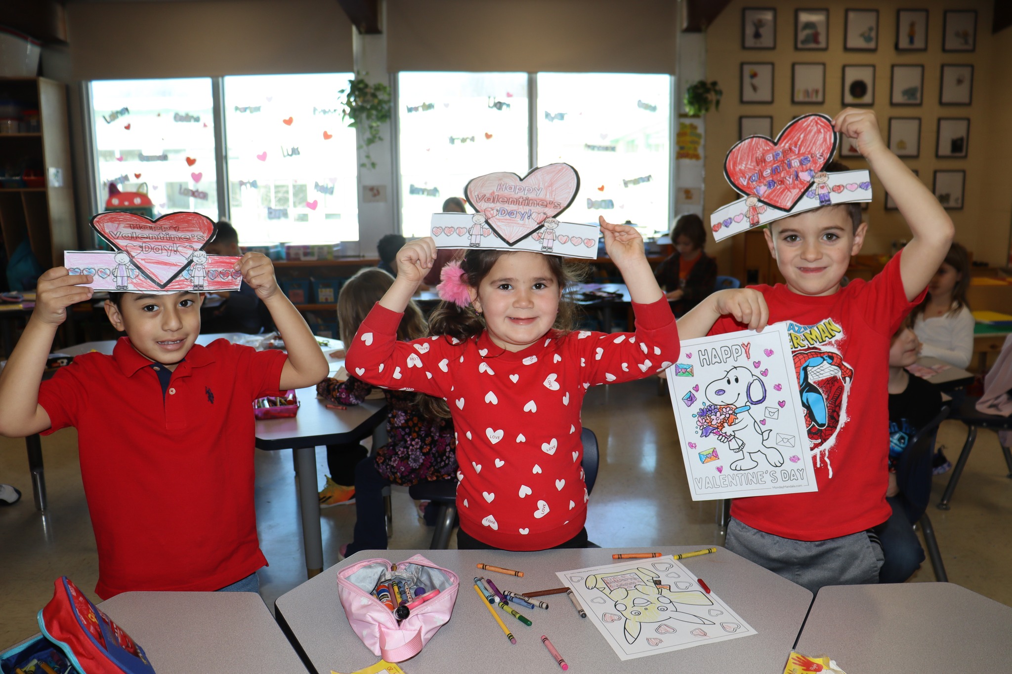 Students holding up valentine crafts
