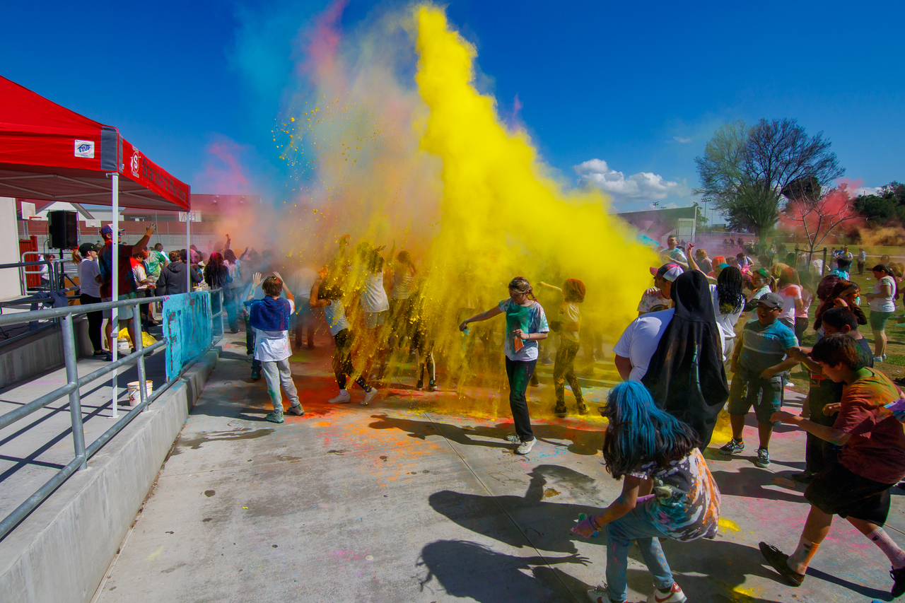 students throwing colored powder in the air