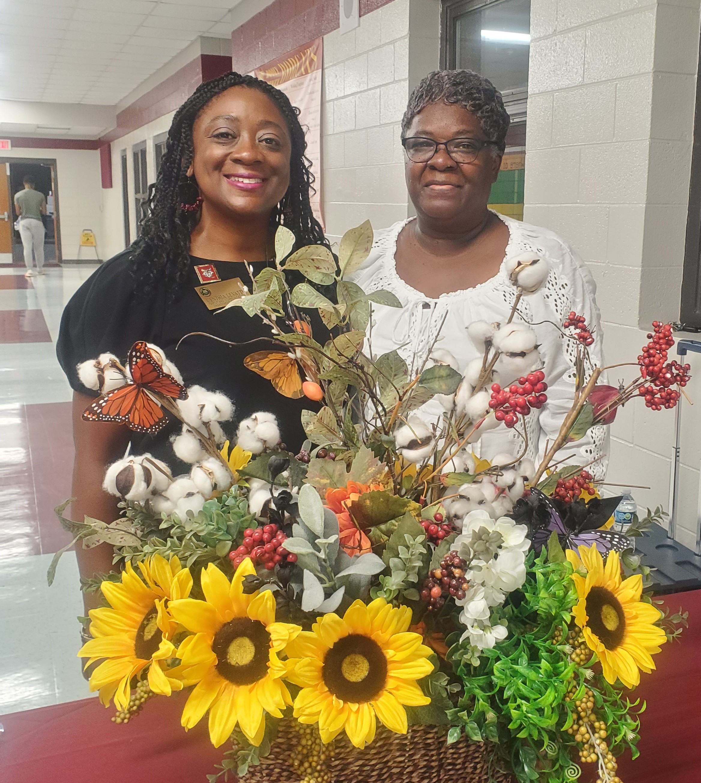 two ladies in front of flower arrangement