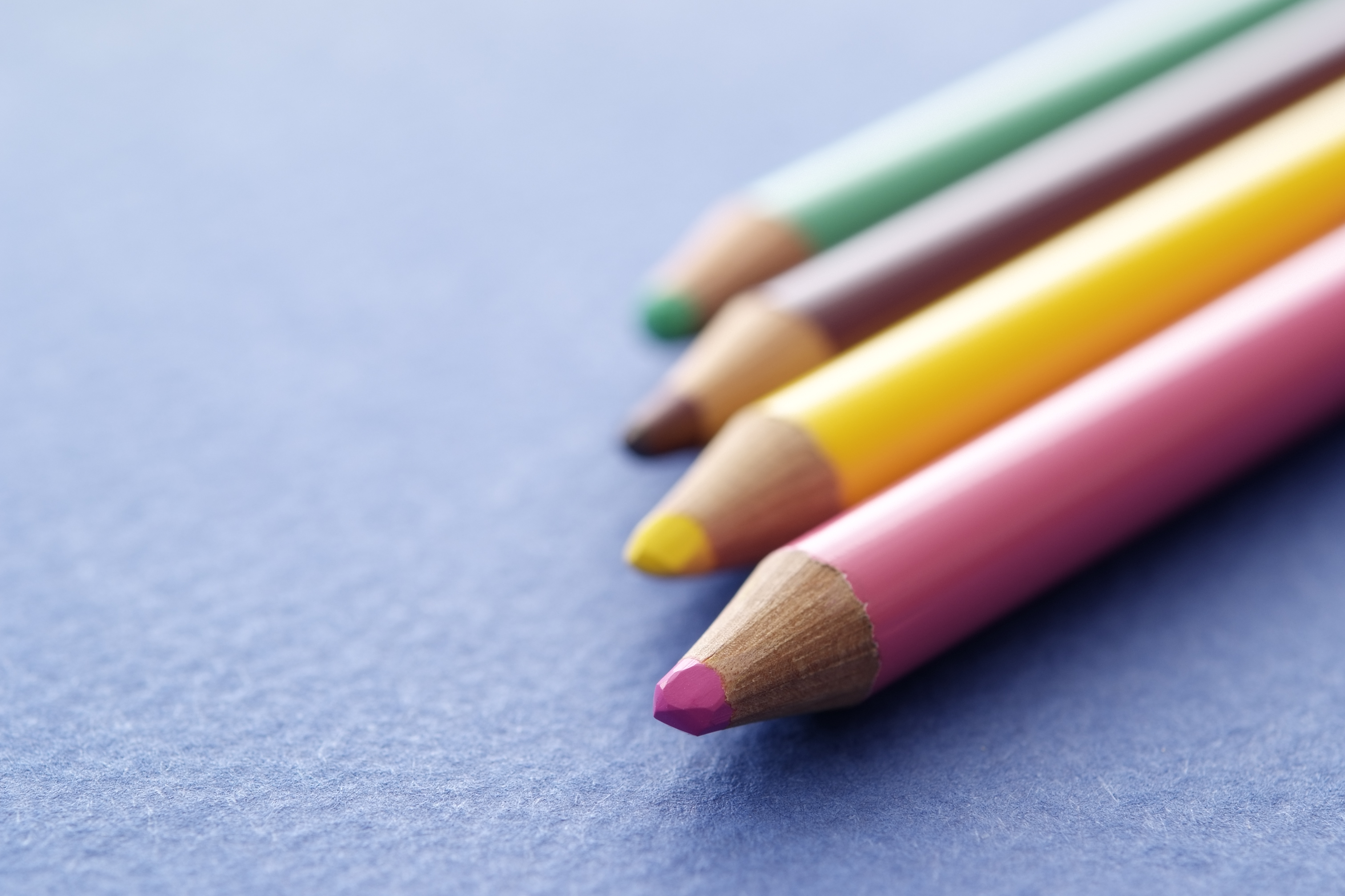 four color pencils on a blue background