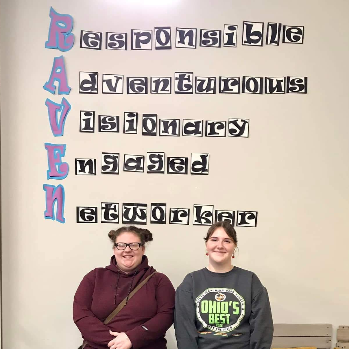 Two girls standing below the RAVEN acronym.