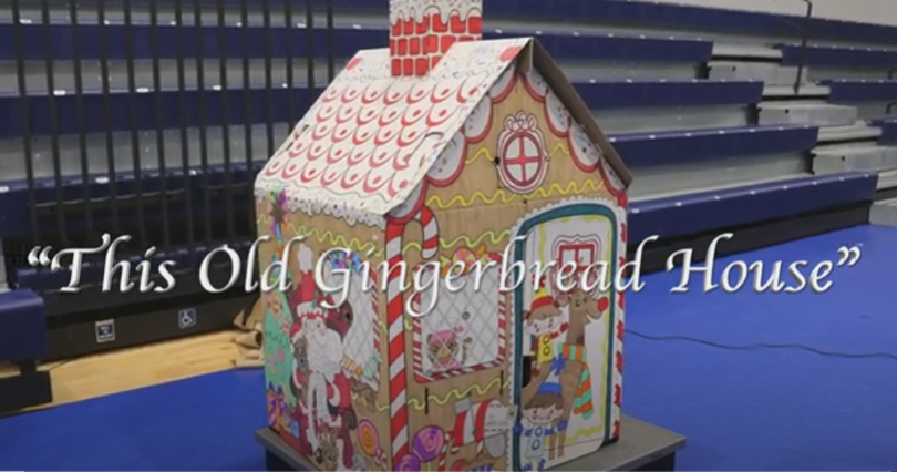 Bleachers in a gym with a cardboard gingerbread house in front of bleachers
