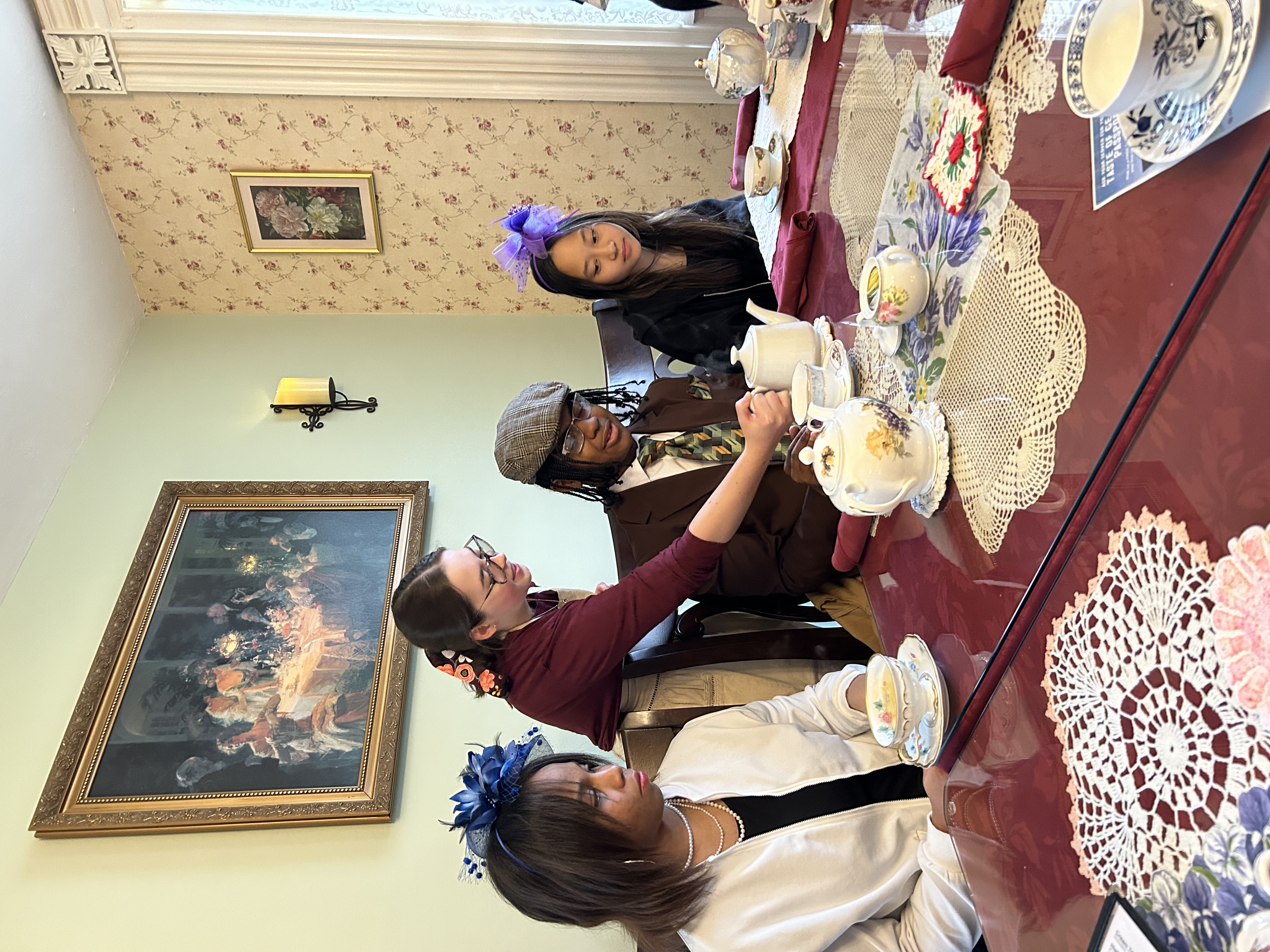 Photo of female students sitting at a table having tea and sweets