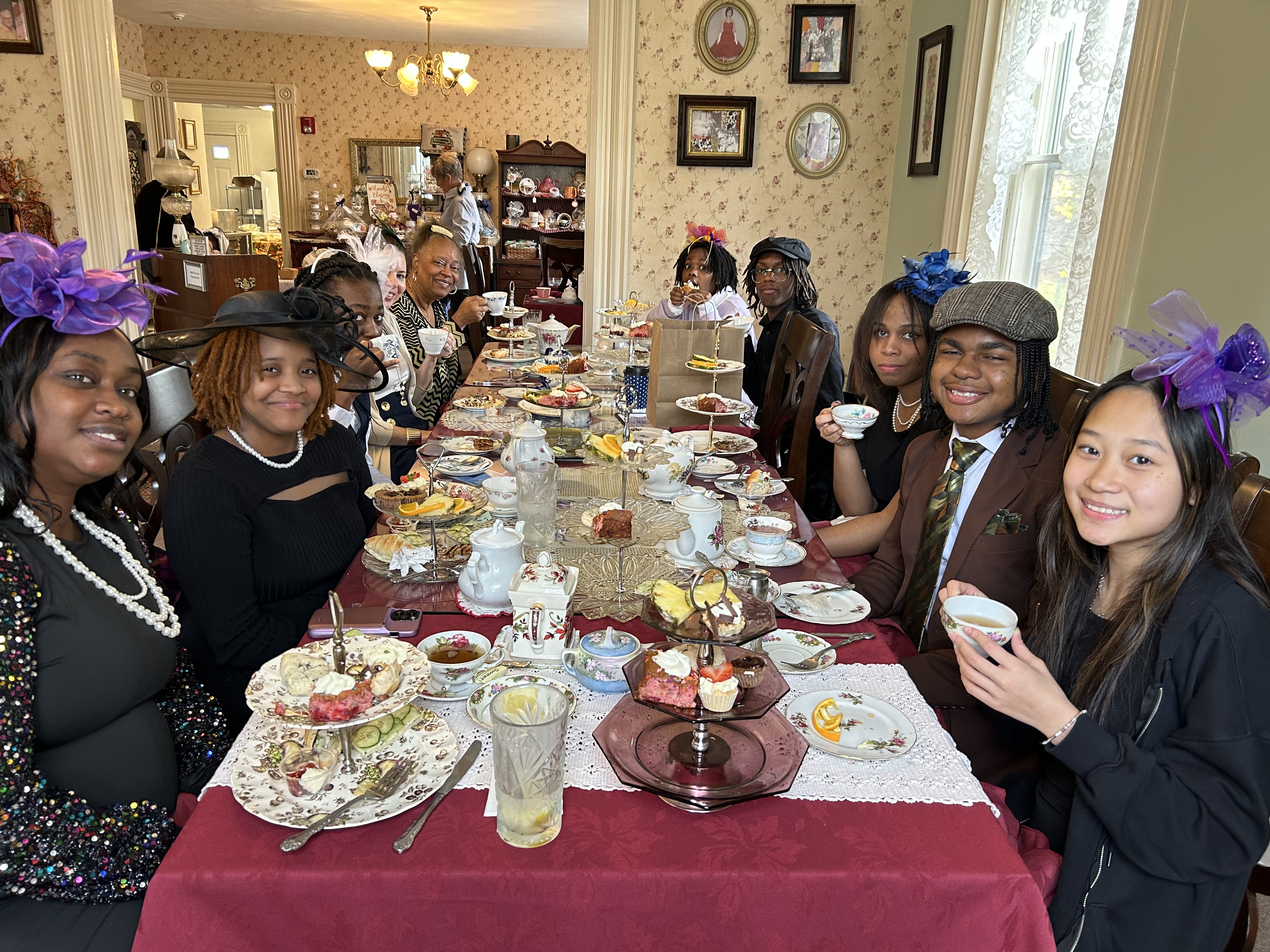 Photo of female students sitting at a table having tea and sweets