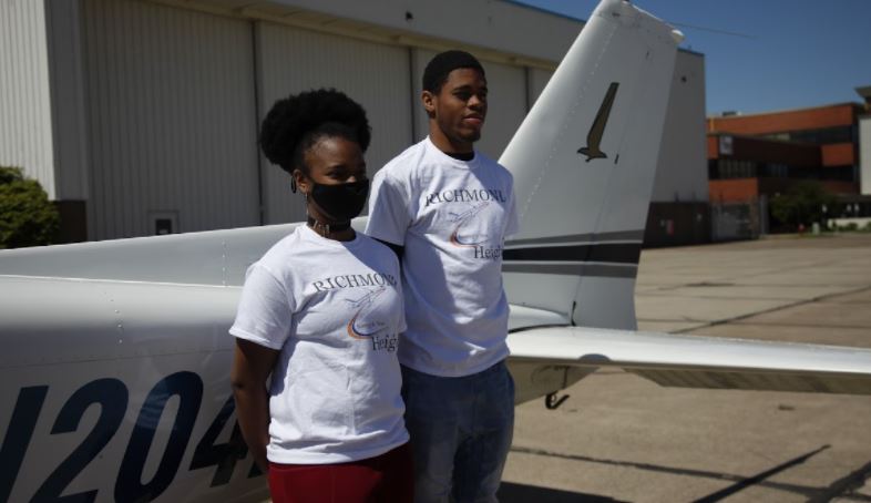 image of students standing next to a plane