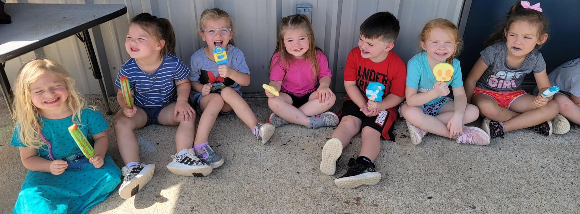 kids sitting outside eating popsicles