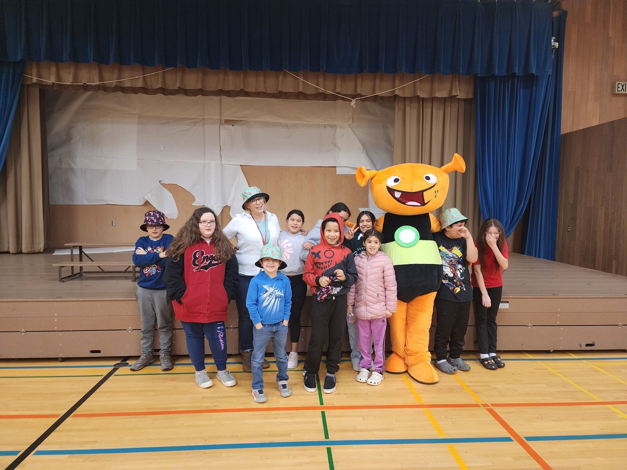 Group of students and a staff member pose with a person in an alien costume