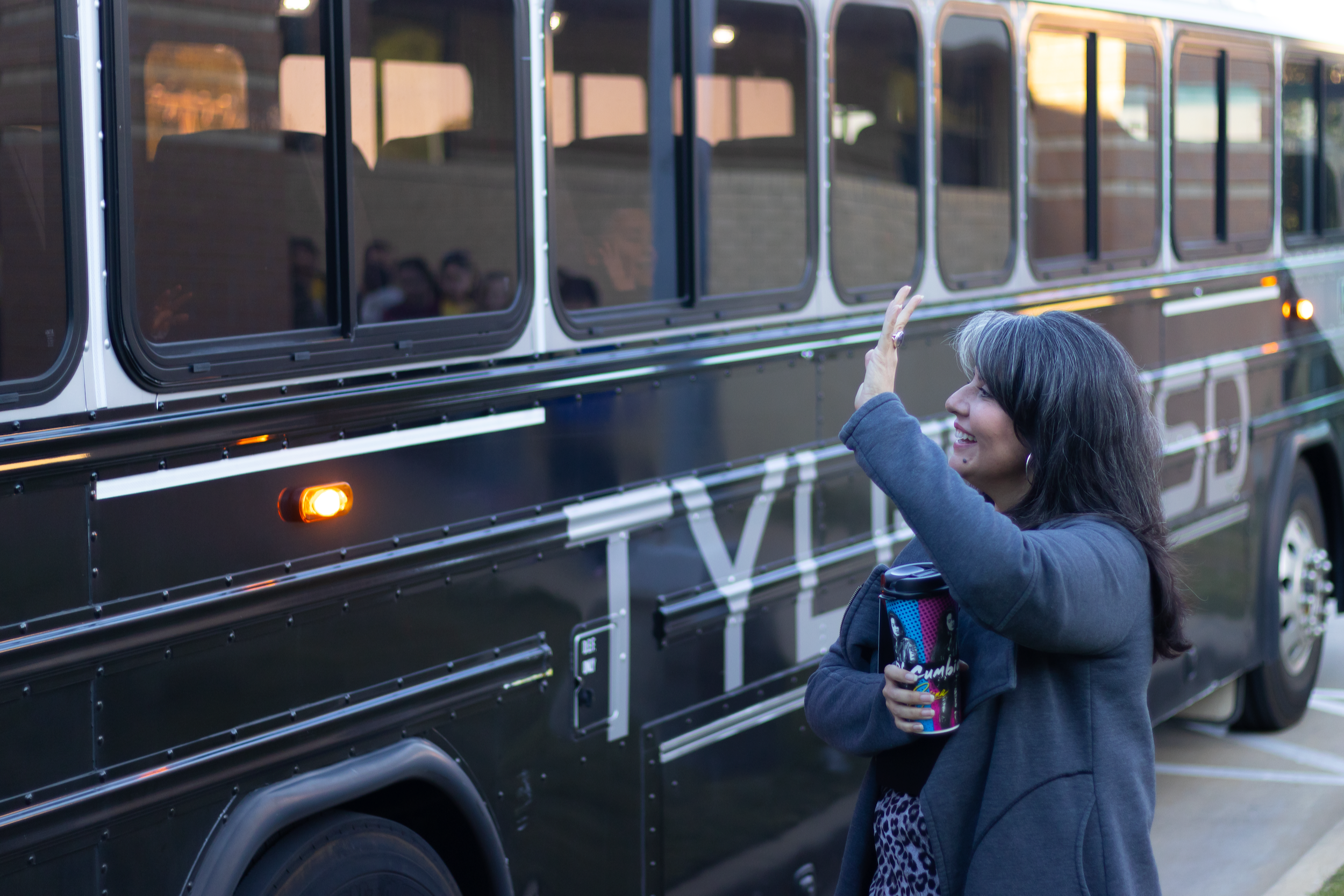 principal waving at students as they are leaving on school bus