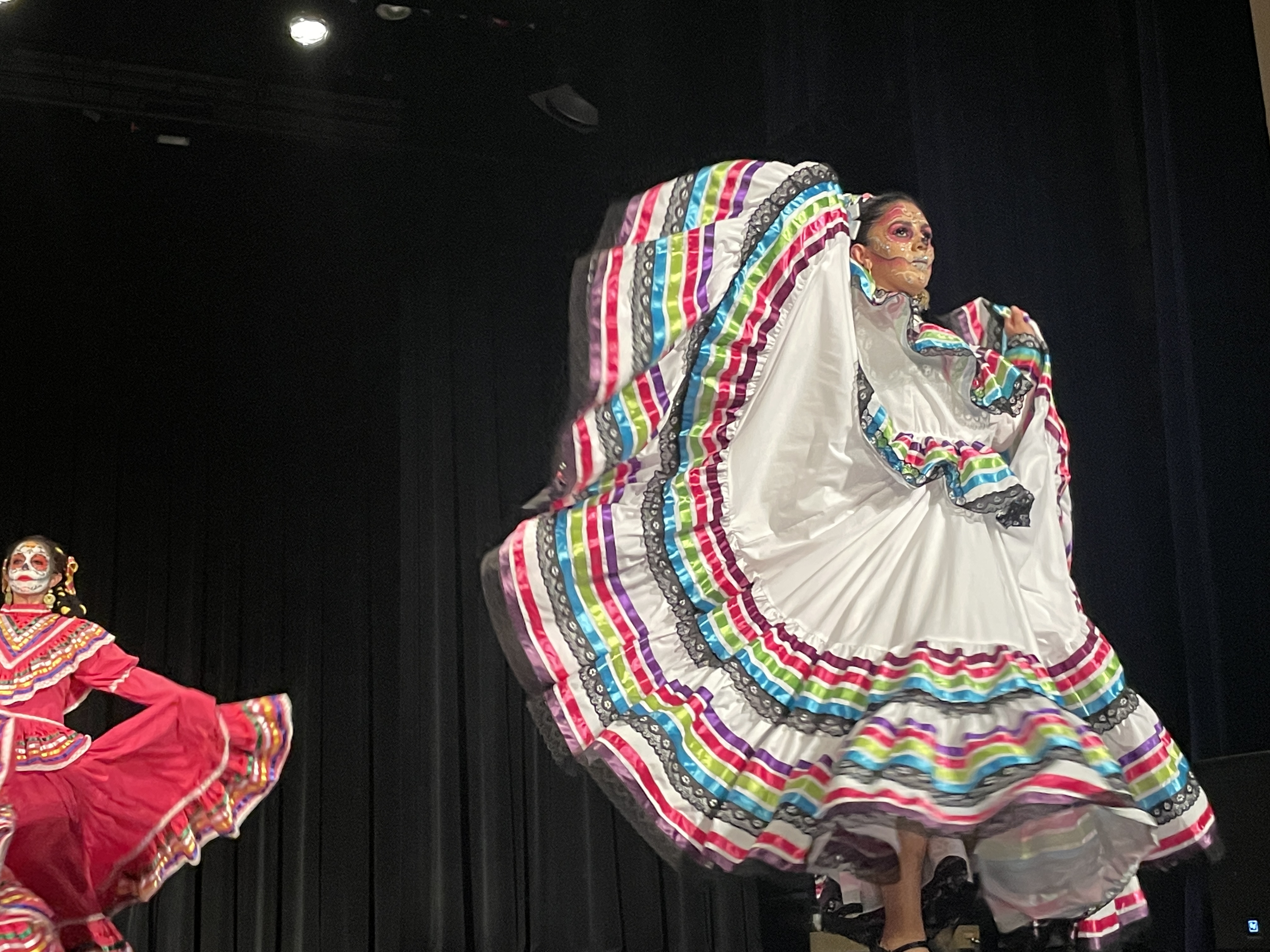 Performer in cultural attire for Dia de los Muertos on stage.