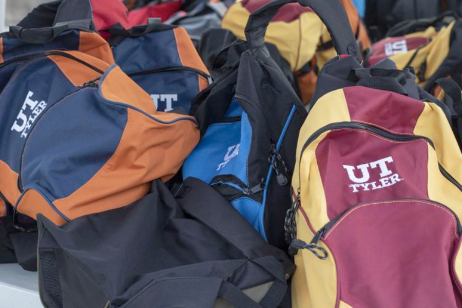 a pile of backpacks with the UT tyler logo on them,