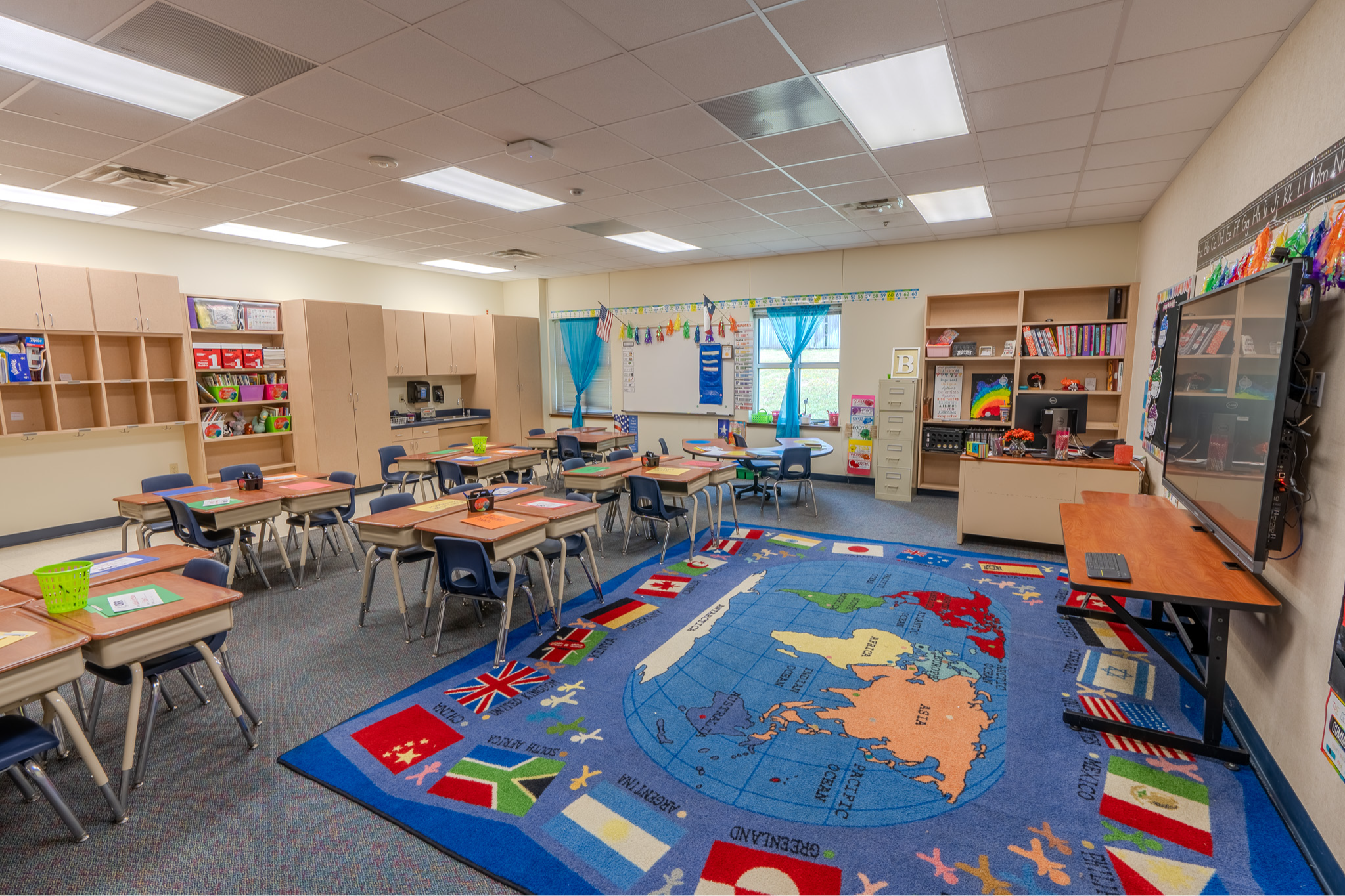 classroom with desks and giant rug on floor with map of world