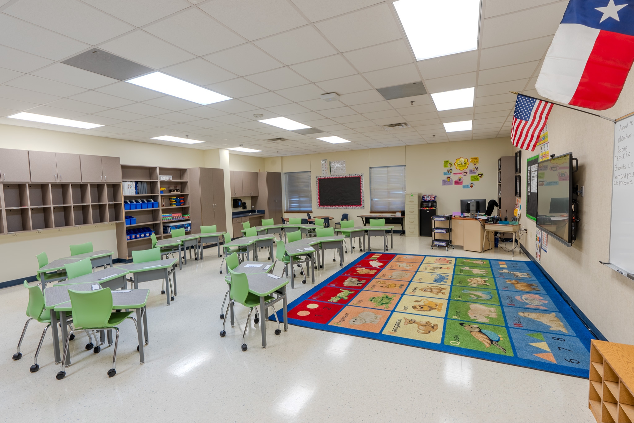 classroom with desks, green chairs, and giant ABC rug