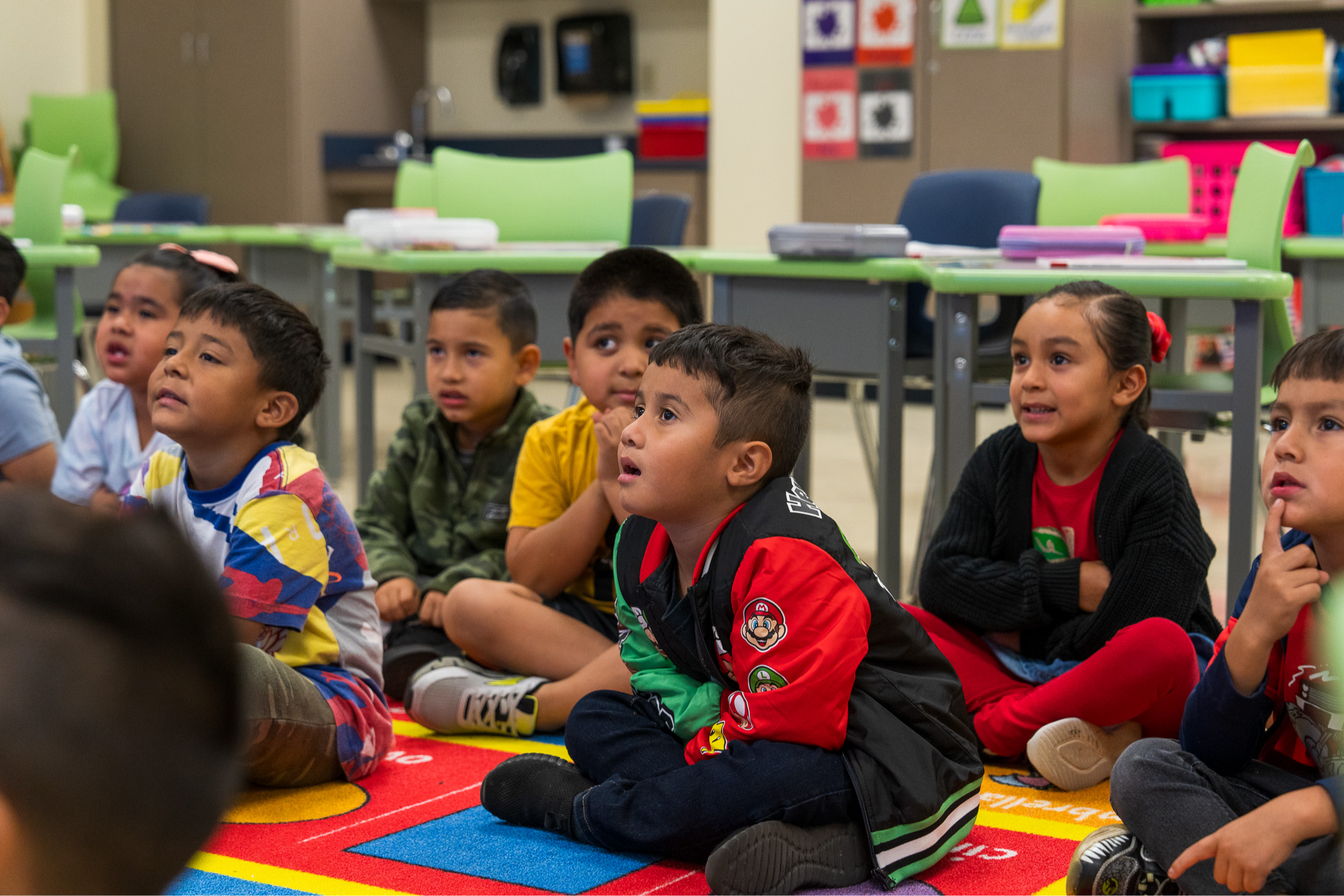 elementary age kids sitting on rug in classroom