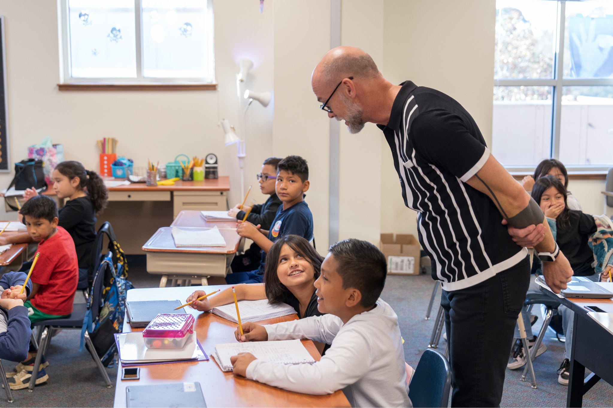 man looking over elementary age students sitting at their desk in classroom