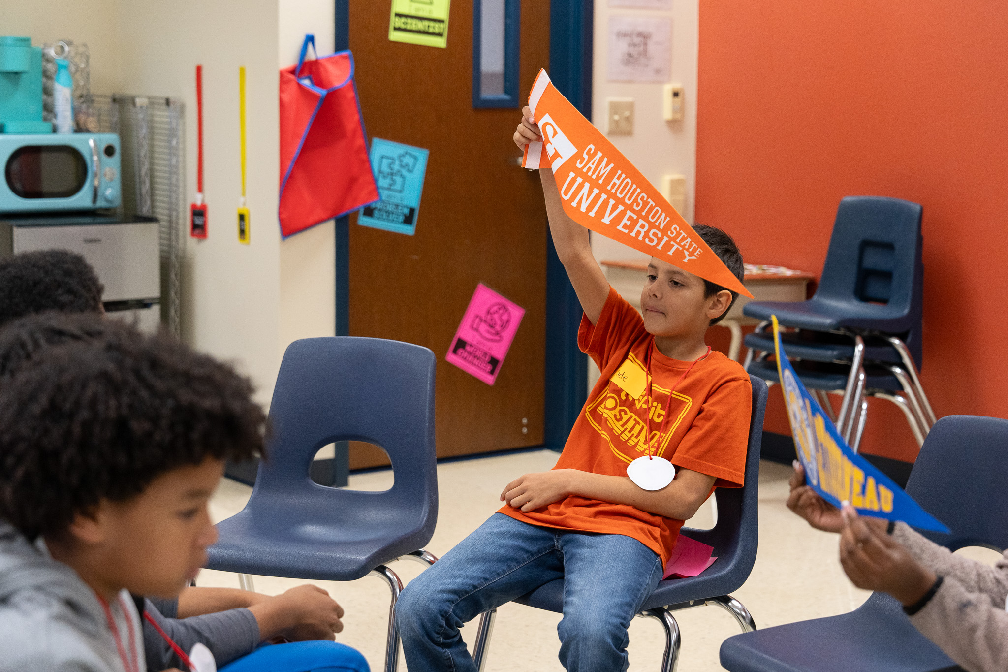 elementary age boy holding a college pennant above his head