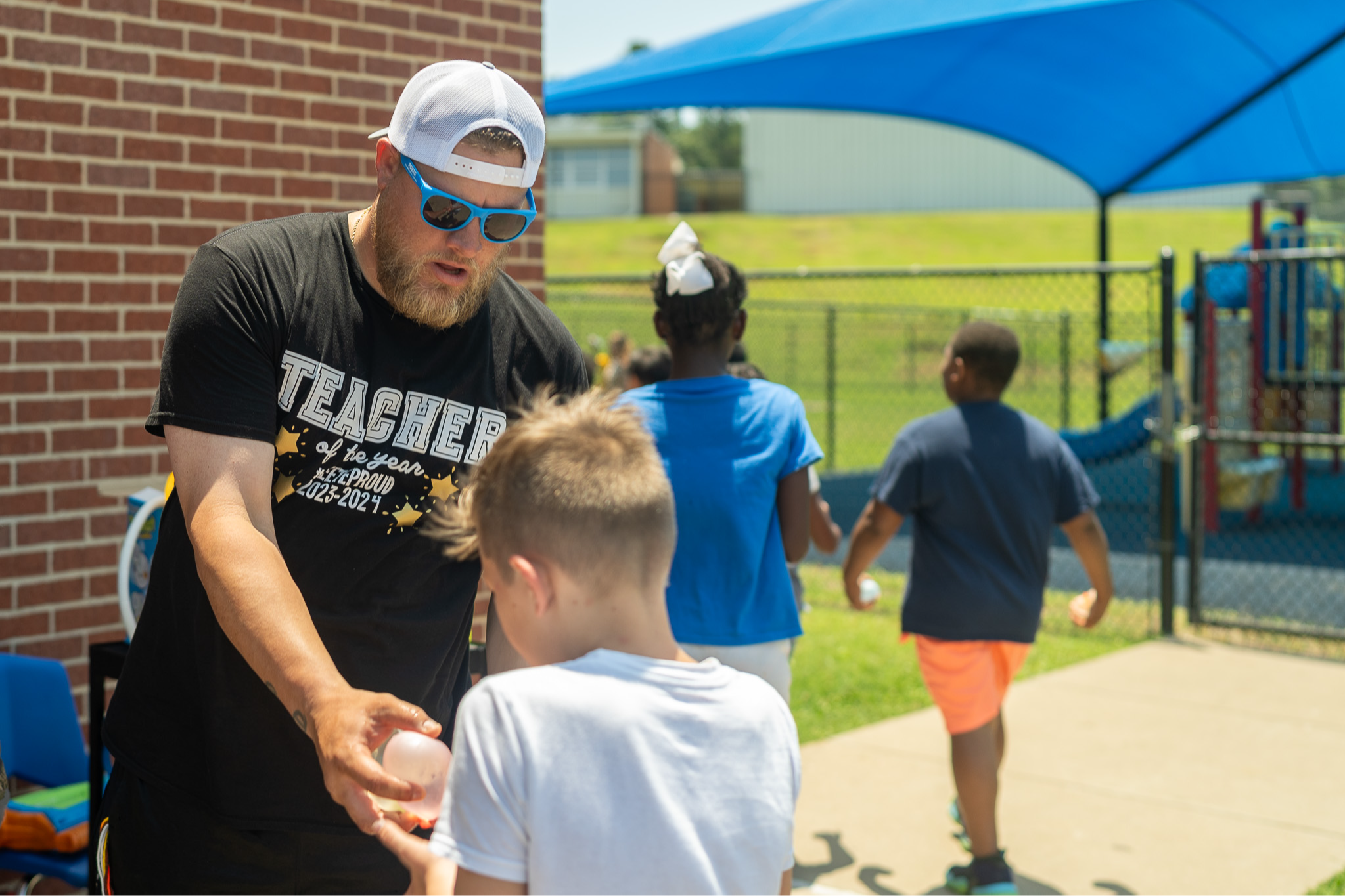 man handing a boy a water balloon