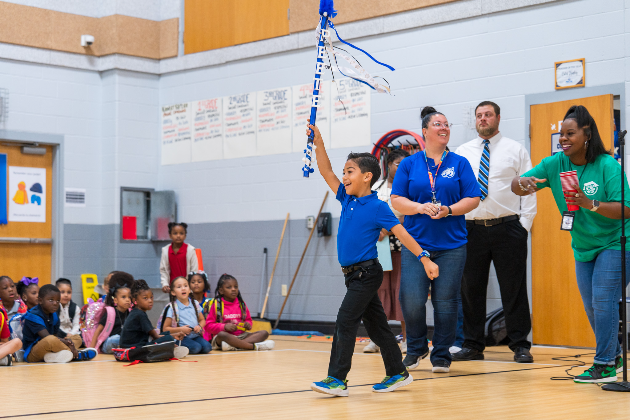 boy holding a blue spirit stick walking in a gym