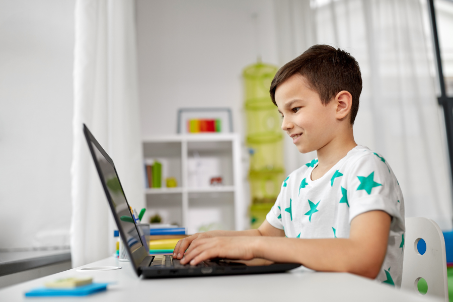 elementary age boy typing on laptop