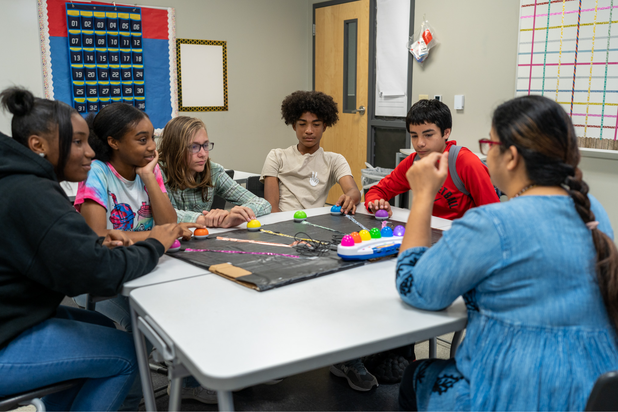 teenagers sitting at table with their teacher