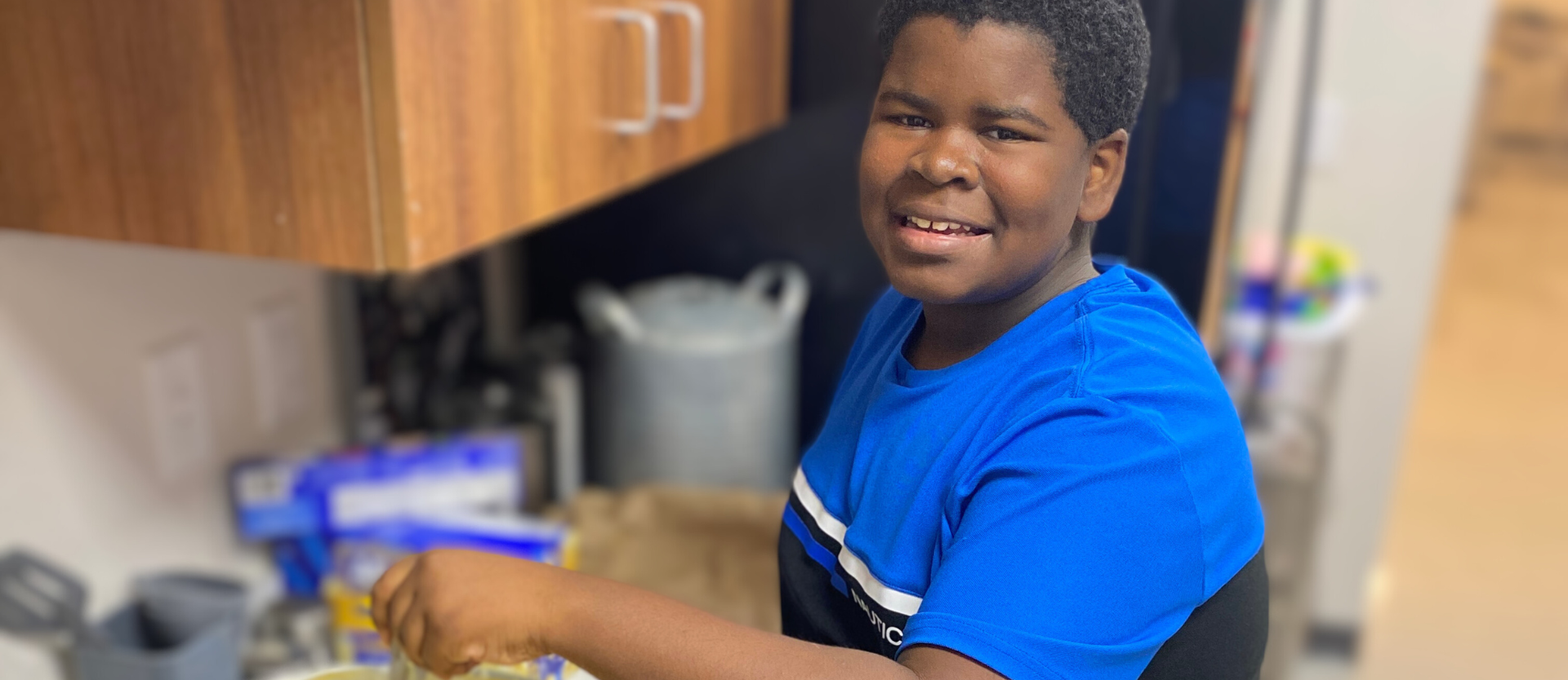 student stirring food in classroom kitchen