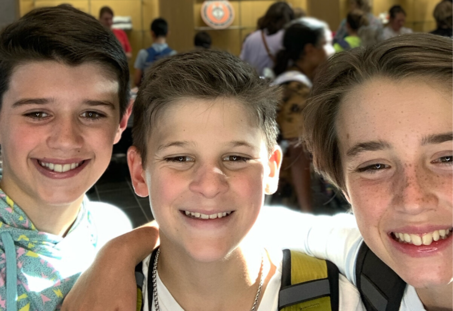 three boys smiling together in the hallway