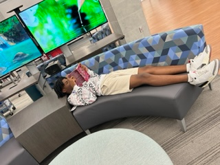 boy laying across couch reading a book reading a book