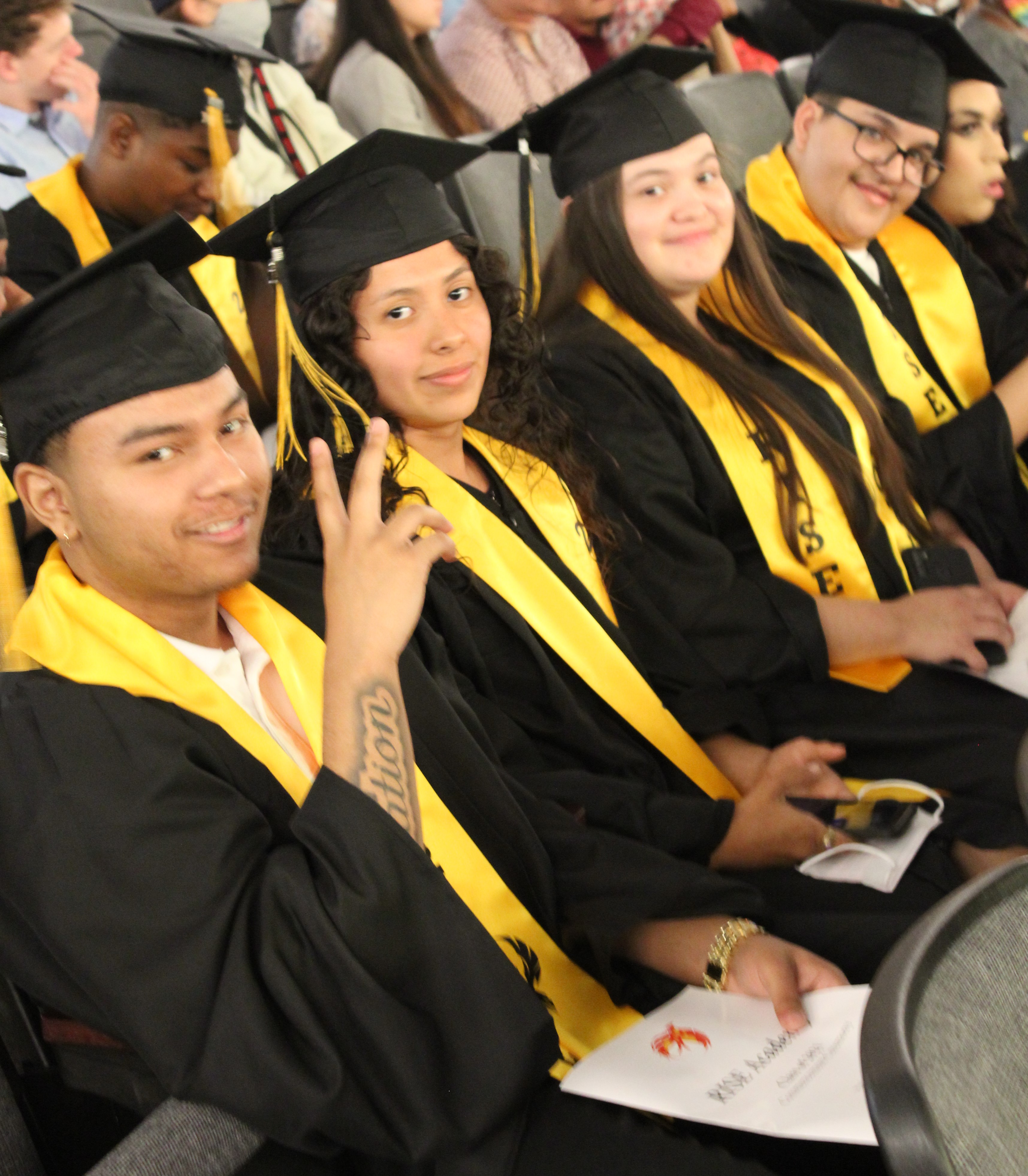 a collection of male and female students seated in the auditorium for graduation
