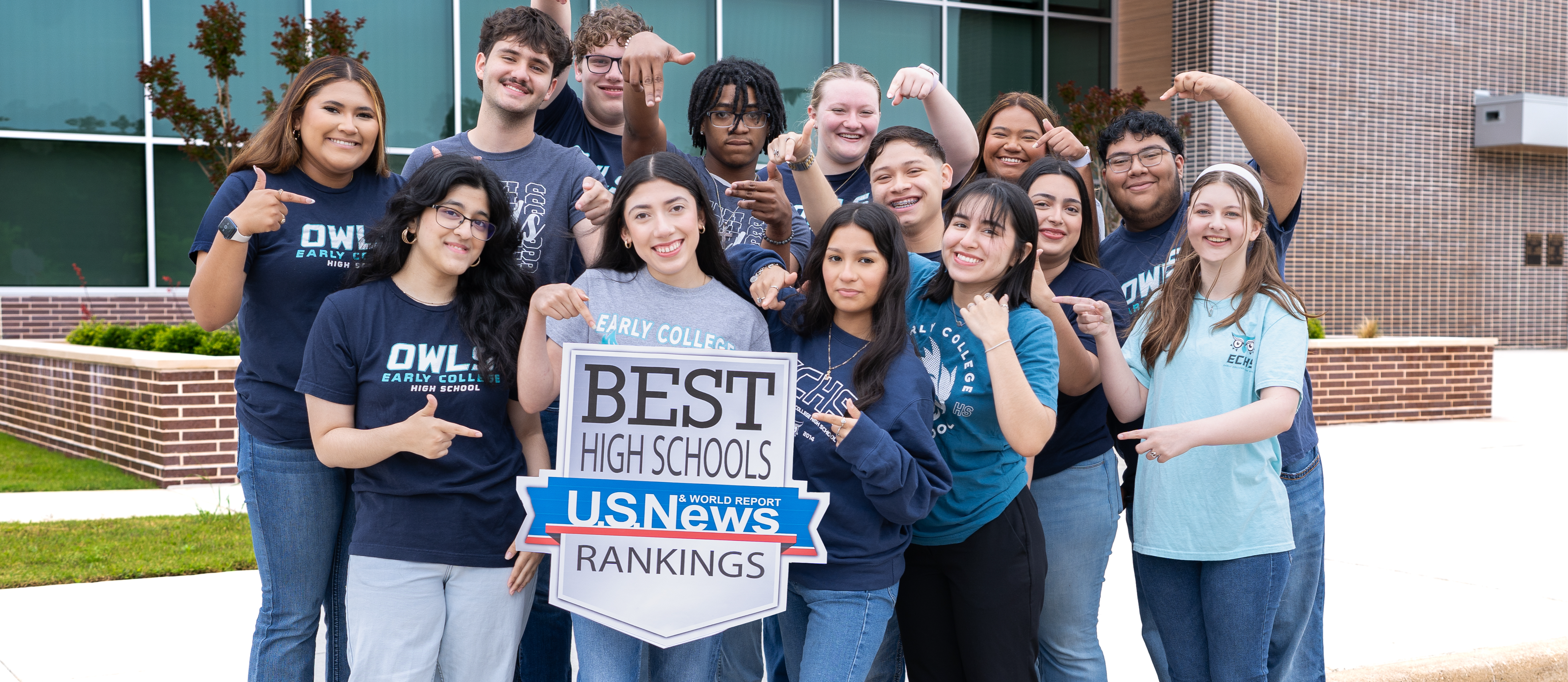 students posing with U.S. news sign