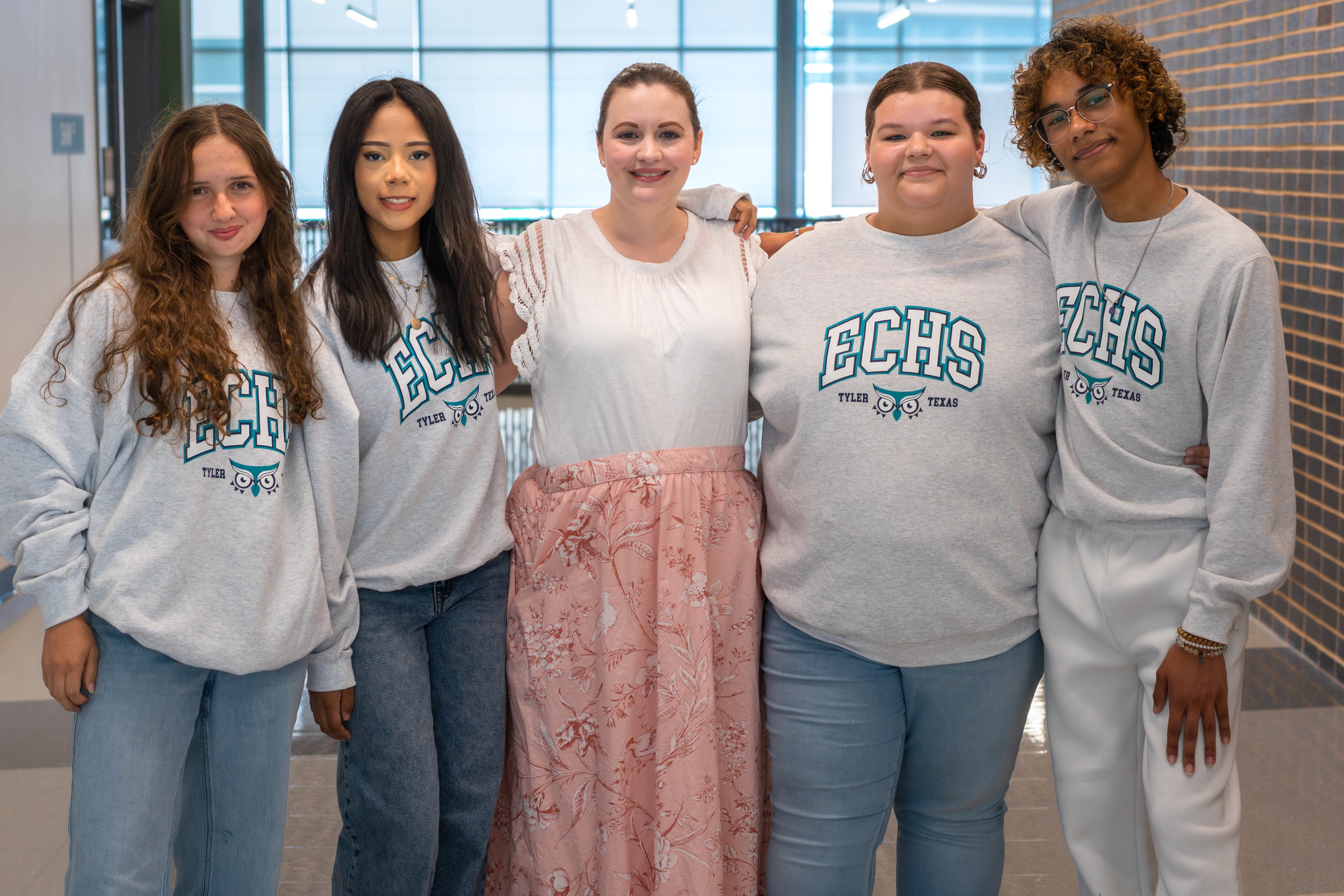teen girls and woman standing with arms around each other