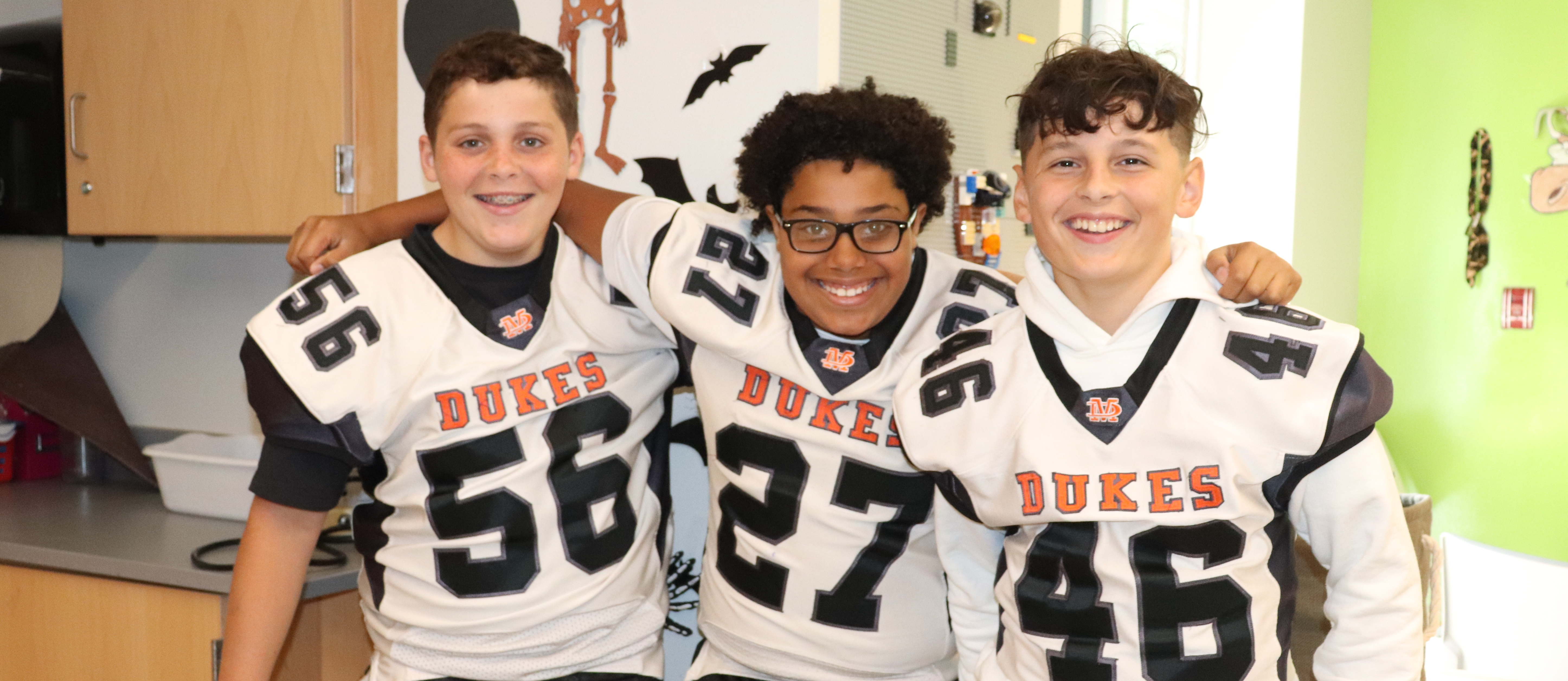 Three students wearing Dukes football jerseys