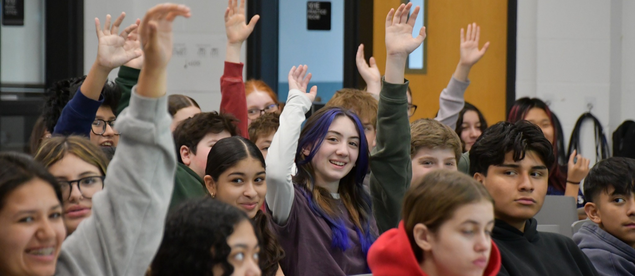 student raising her hand in a cluster of other students