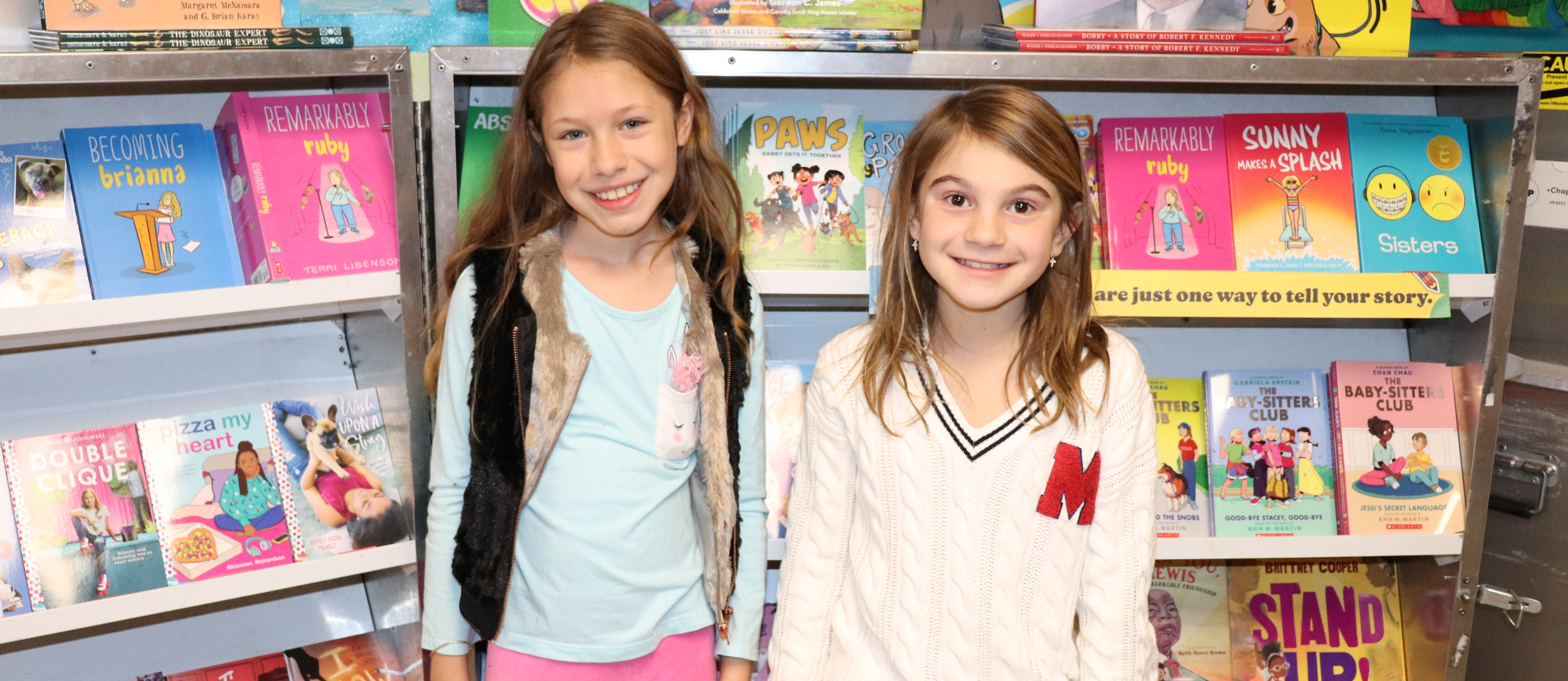 Two girls standing in front of a book display