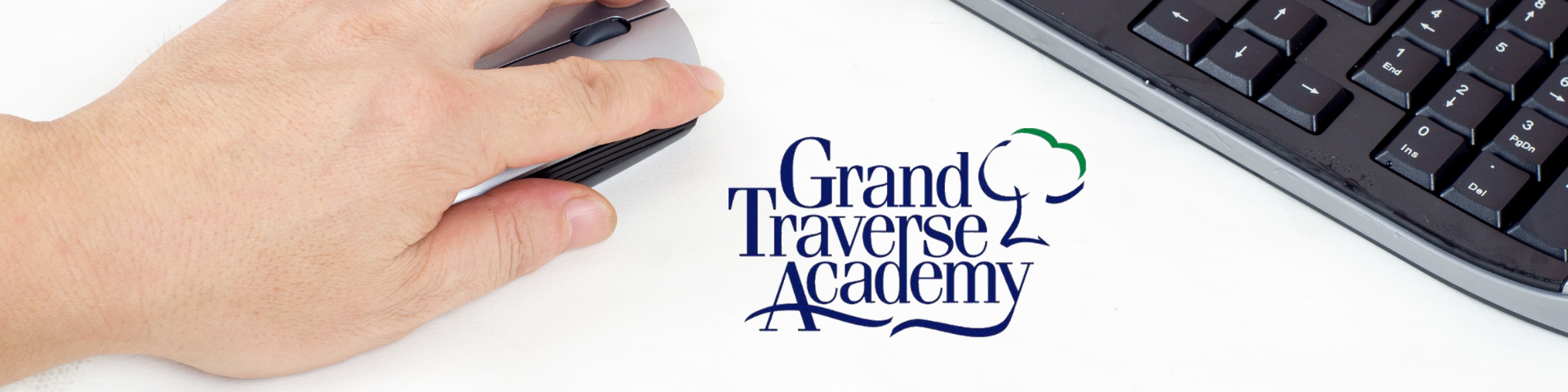 Hand on computer mouse with Grand Traverse Academy Text overlay