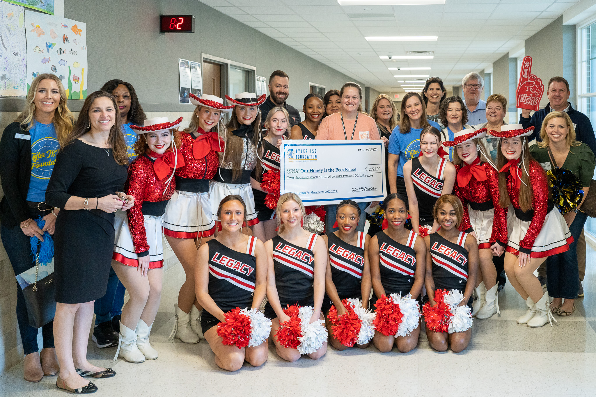 group of people standing in a hallway holding a giant check