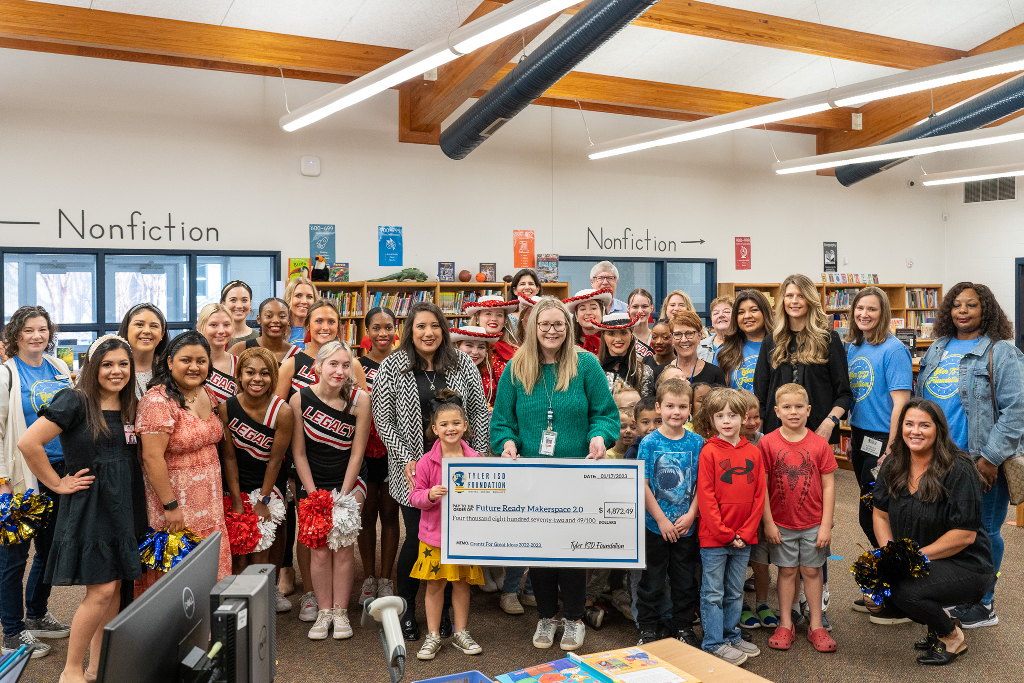 group of people standing in a hallway holding a giant check