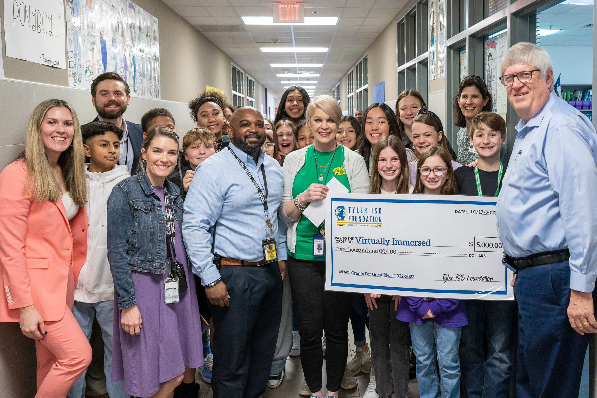 group of people standing in a hallway holding a giant check