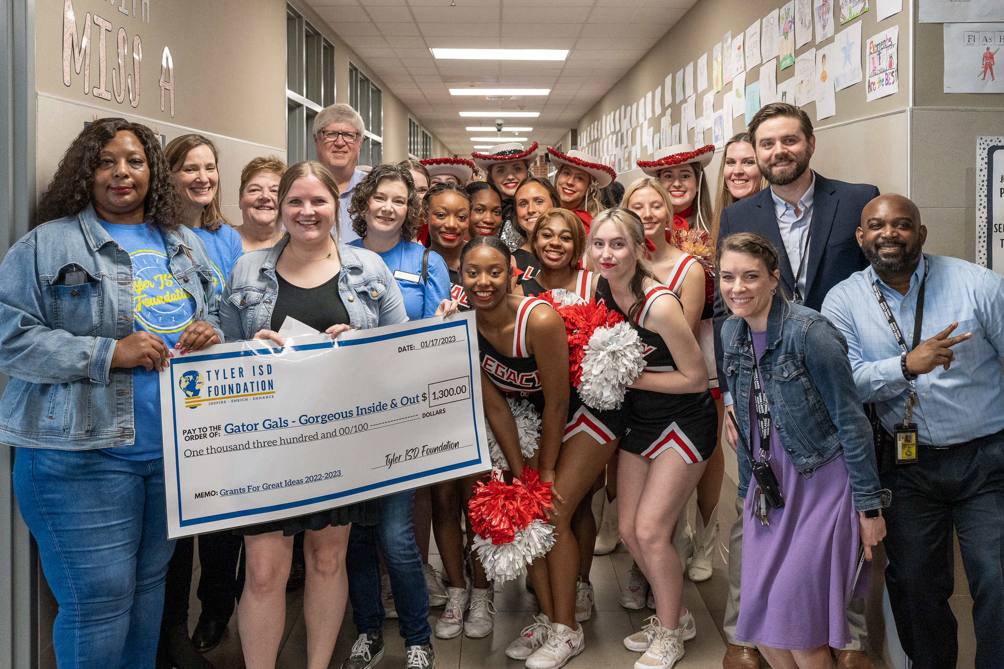 group of people standing in a hallway holding a giant check